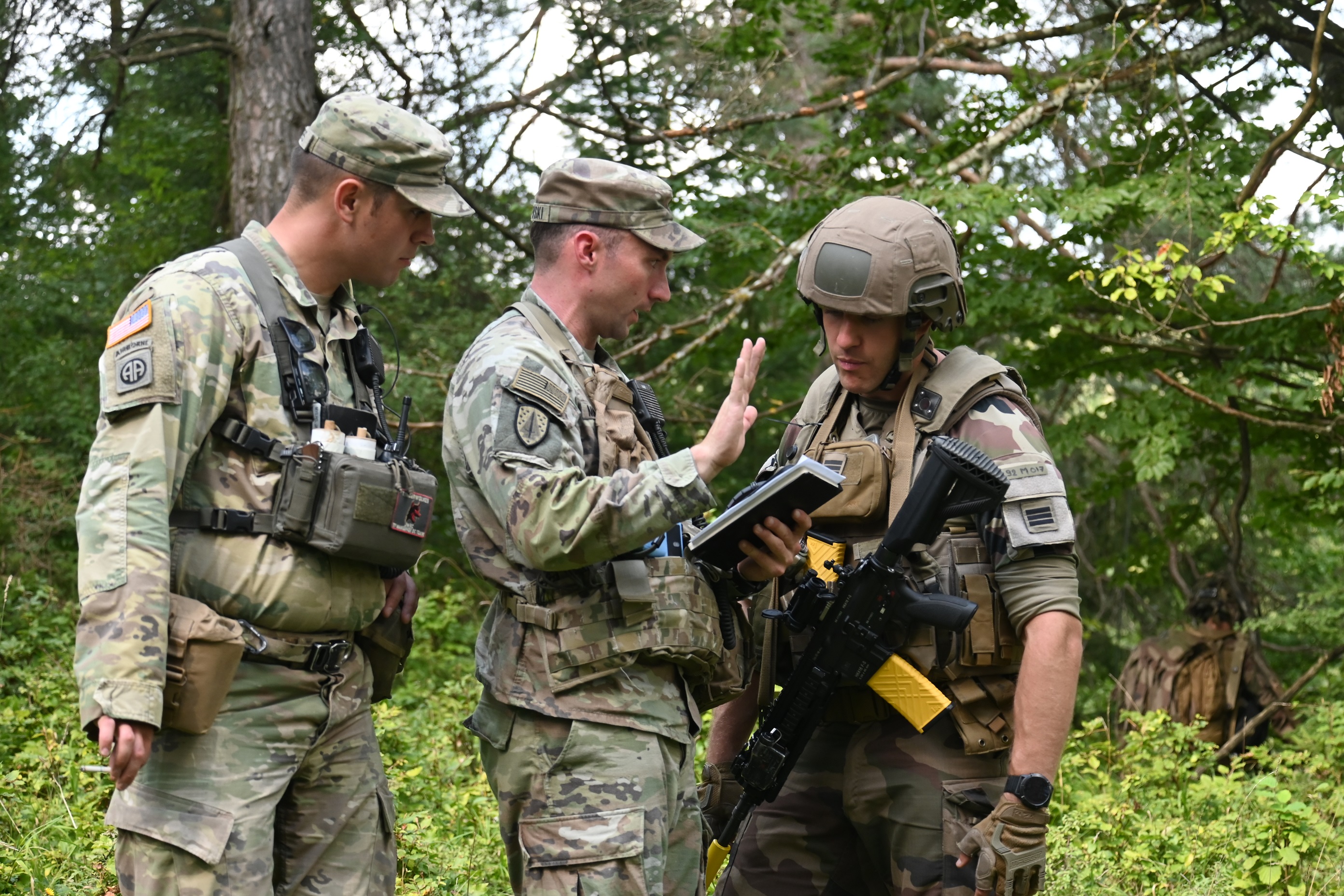 2 militaires américains s'entretiennent avec un Français lors de l'exercice Saber Junciton en Allemagne.