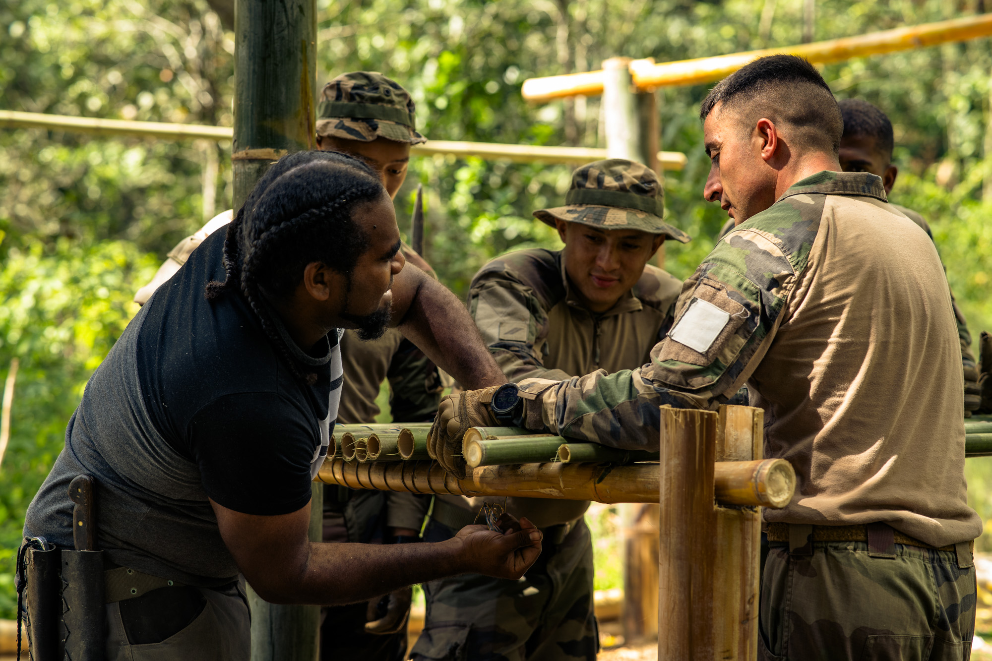 Avec l’aide des soldats, Gema construit une table en bambou, en vue du mariage. 