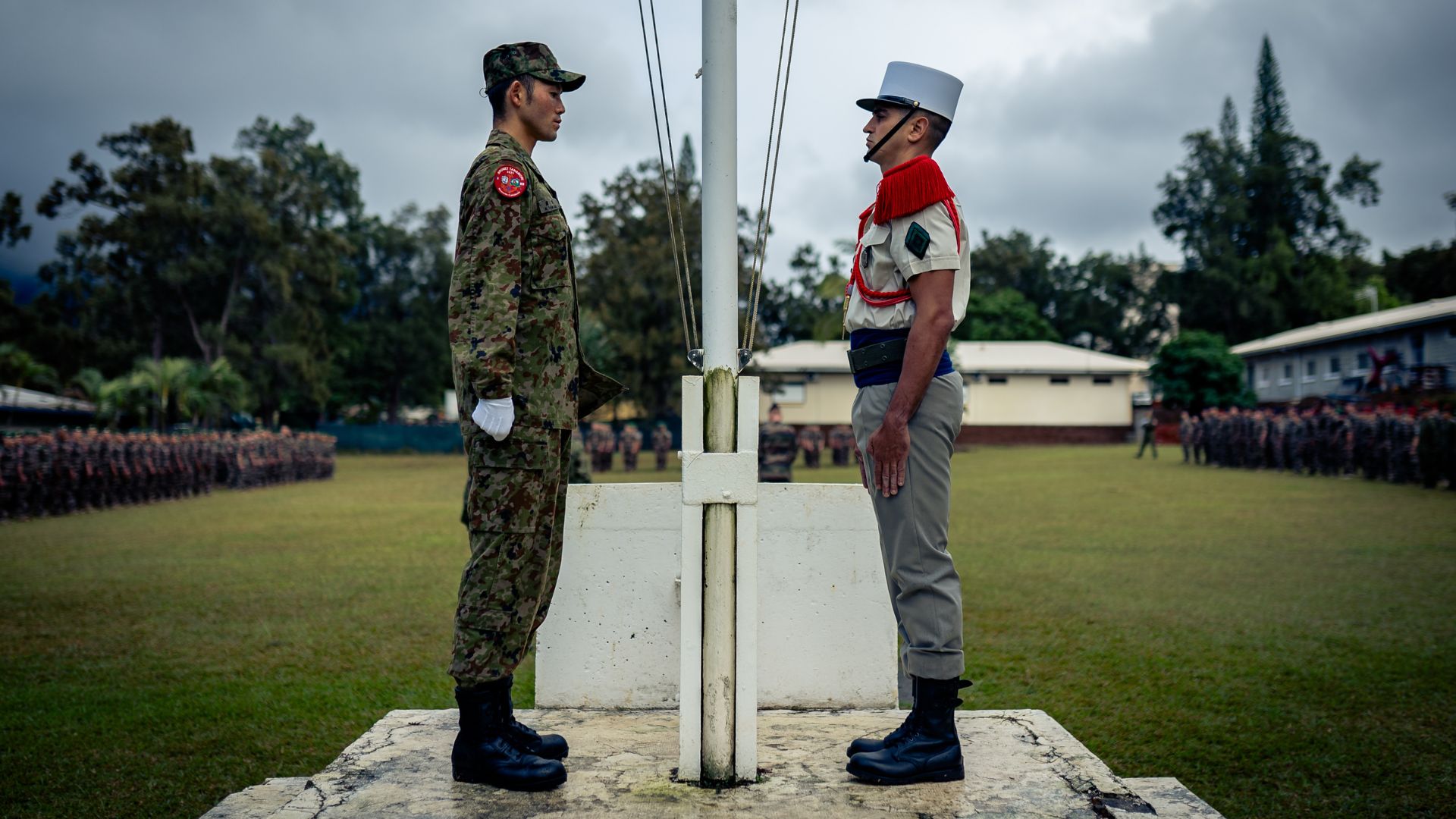Un soldat japonnais et français devant le mât des couleurs de la place d'armes du RIMaP-NC.